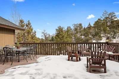 a deck covered in snow with tables and chairs at Fallen Leaf Hideaway Castle Estate in Big Bear Lake