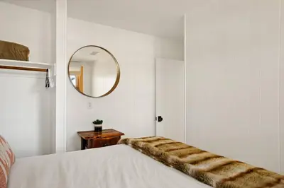 a white room with a bed with a mirror at Lakefront View Stunner in Big Bear Lake