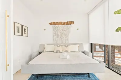 a white bedroom with a bed with a chandelier at Lakefront Modern A Frame in Big Bear Lake