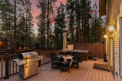 a deck with a grill and a table and chairs at Knoll Lake Cabin in Big Bear Lake in Big Bear Lake