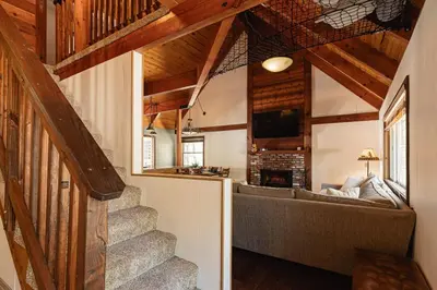 a living room with a staircase in a house at Knoll Lake Cabin in Big Bear Lake in Big Bear Lake