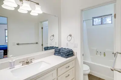 a white bathroom with a sink and a mirror at Serene Pine Mountain Club Home with Pool Access! in Pine Mountain Club