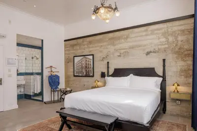 a bedroom with a white bed and a brick wall at Hotel San Buena in Ventura