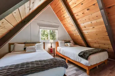 two beds in a attic bedroom with wooden ceilings at The Teddy Bear Cabin! Large Patio! in Big Bear City