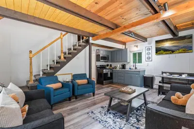 a living room with blue furniture and a staircase at The Teddy Bear Cabin! Large Patio! in Big Bear City