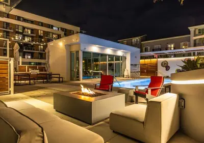 a patio with a fire pit and a pool at night at @ Marbella Lane - Grand 2BR w/ Beach & Ocean Views in Long Beach