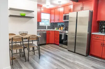 a kitchen with red cabinets and a table and a refrigerator at Beautiful hillside gateway in Los Angeles