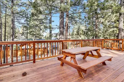 a wooden deck with a picnic table on it at Kozy Cabin Big Bear~ Walk to Village & Lake Cottage~ in Big Bear Lake