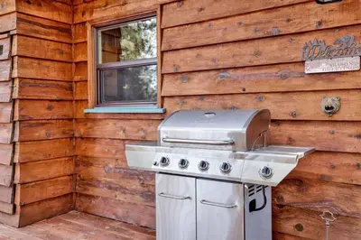 a barbecue grill sitting in front of a wooden wall at Kozy Cabin Big Bear~ Walk to Village & Lake Cottage~ in Big Bear Lake