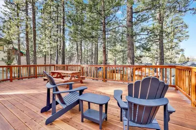 a deck with three chairs and a picnic table at Kozy Cabin Big Bear~ Walk to Village & Lake Cottage~ in Big Bear Lake