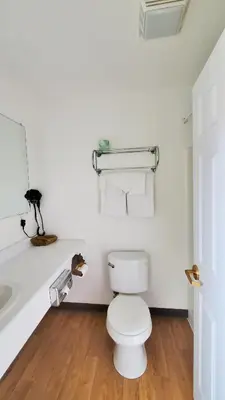 a white bathroom with a toilet and a sink at Corral Creek Lodge in Kernville