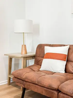 a brown couch with a pillow and a table with a lamp at Modern 2-Bedroom Gem Close to Beverly Hills - DOH2 in Los Angeles