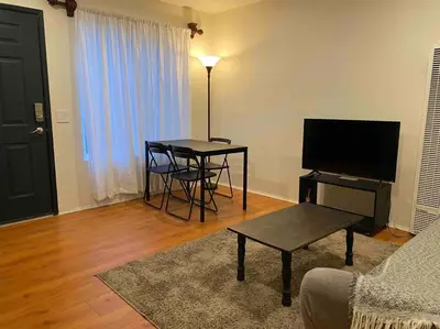 a living room with a table and a television at Beach Gateway Full Kitchen 1 Bedroom Duplex in Manhattan Beach