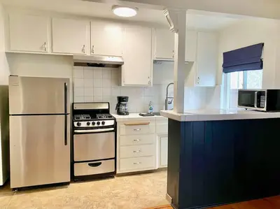a kitchen with a stainless steel refrigerator and white cabinets at Beach Gateway Full Kitchen 1 Bedroom Duplex in Manhattan Beach