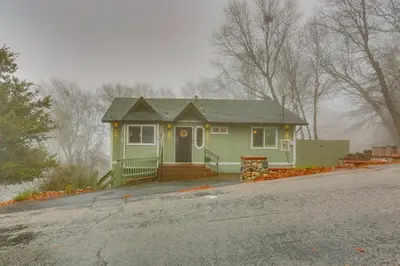a small green house on the side of a road at Mid-Century Mod Cottage, Steps to Lake Gregory! in Crestline