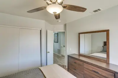 a bedroom with a ceiling fan and a mirror at Victorville Home with Fenced Backyard and Patio! in Victorville
