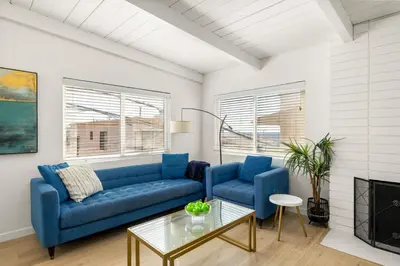 a living room with a blue couch and a table at NEW! Ocean View Mid-Century Modern Beach House in Manhattan Beach