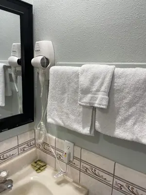 a bathroom with white towels and a mirror and a sink at La Cienega Inn Motel in Los Angeles