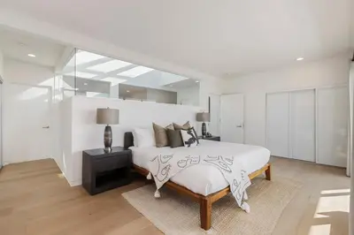a white bedroom with a large bed and a table at Malibu Breeze - hot tub, ocean view, steps to beach in Malibu