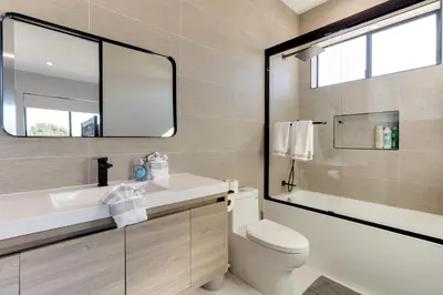 a bathroom with a sink and a toilet and a mirror at Brand New Modern 4 Bedroom House Pickfair Village in Los Angeles