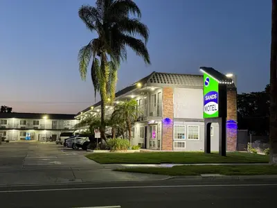 a gas station with a palm tree in front of a building at Sands Motel in Riverside