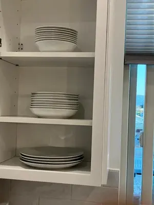 a white cabinet with plates and dishes in it at The Verna Mae in Los Angeles