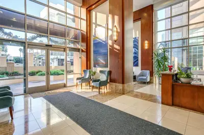 a lobby with chairs and tables and large windows at Luxe Long Beach Condo with Pool 1 Mi to Shoreline! in Long Beach