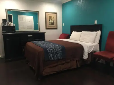 a hotel room with a bed and two chairs at Crenshaw Inn Motel in Los Angeles