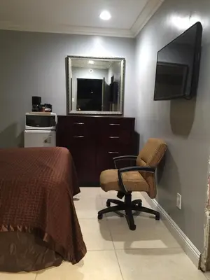 a bedroom with a bed and a chair and a mirror at Crenshaw Inn Motel in Los Angeles