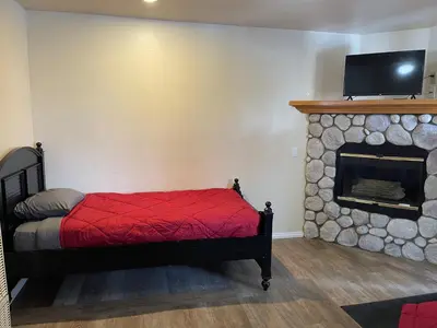 a bedroom with a fireplace and a bed with a red blanket at Snow Bear Lodge in Big Bear Lake