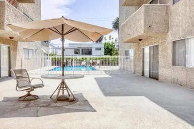 a table and a chair and an umbrella in a courtyard at Blueground Fairfax pool nr mall dining LAX-1185 in Los Angeles
