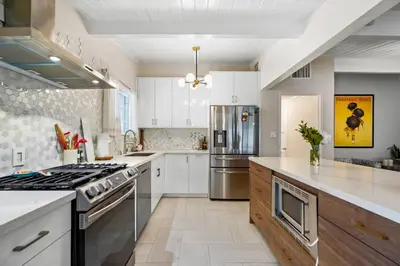 a large kitchen with white cabinets and stainless steel appliances at Valley Glen Getaway in Van Nuys