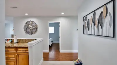 a kitchen with white walls and a counter with feathers on the wall at H&H Modern Lux 4BD 1 King Suite 3 Queen SoCal Disney in Westminster