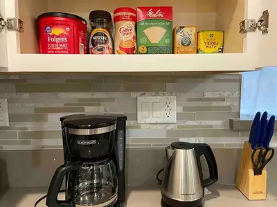 a coffeemaker sitting on a kitchen counter next to a shelf at New! Cozy Gated 3BR, 2BA Vacation Home in Rosemead