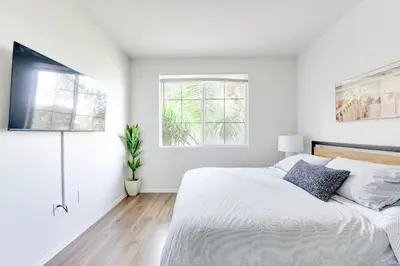 a white bedroom with a bed and two windows at Spacious, Comfortable, and Central Condo in Los Angeles