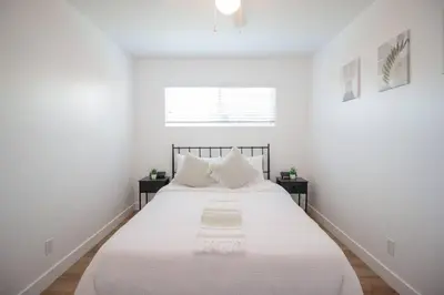 a white bedroom with a large bed with white sheets at Comfortable & Modern 3BD/2BA Home -pet friendly! in Lawndale