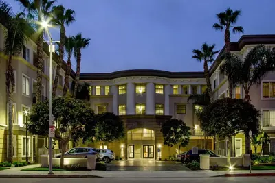 a large building with palm trees in front of it at Luxe MDR apartment,Parking, Gym, Pool, jacuzzi,BBQ in Los Angeles