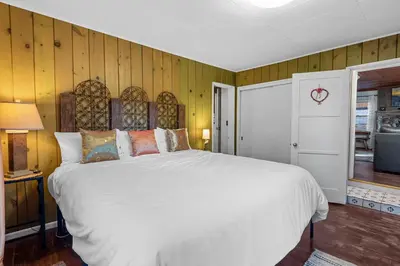a bedroom with a large white bed and wooden walls at Warbler's Roost - Perfect vintage cabin in the woods in Big Bear Lake