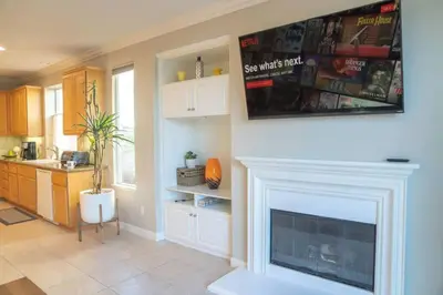 a living room with a fireplace and a kitchen at Spacious Disney Retreat with Pool Table Fire Pit in Placentia