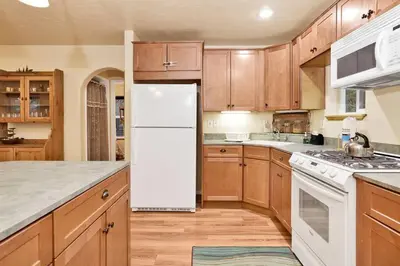 a kitchen with wooden cabinets and a white refrigerator at Mount Berkley Big Bear~ Walk to Village~ Games~ in Big Bear Lake