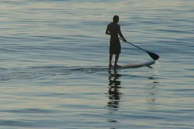 a man standing on a paddle board in the water at Malibu Best Kept Secret in Malibu