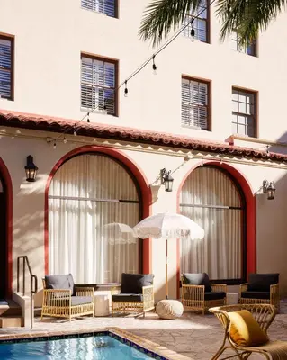 a pool with chairs and an umbrella next to a building at Pasadena Hotel & Pool in Pasadena