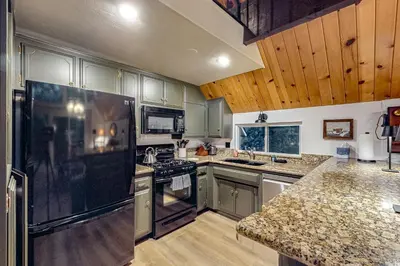 a kitchen with stainless steel appliances and wooden cabinets at Pinecrest Paradise in Crestline