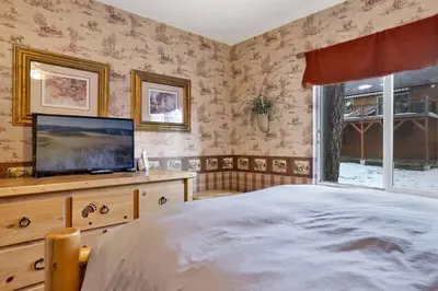 a bedroom with a bed and a flat screen tv at Big Bear Happy Place~ Hot Tub~ Games~ Walk to Village~ in Big Bear Lake