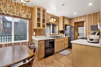 a kitchen with wooden cabinets and a large window at Big Bear Happy Place~ Hot Tub~ Games~ Walk to Village~ in Big Bear Lake