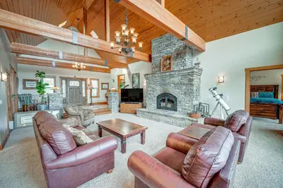 a living room with leather furniture and a stone fireplace at Pine Mountain Club Cabin with Private Deck and Views! in Pine Mountain Club