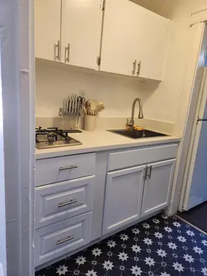 a kitchen with white cabinets and a sink and a stove at Eight Street Apartments in Long Beach