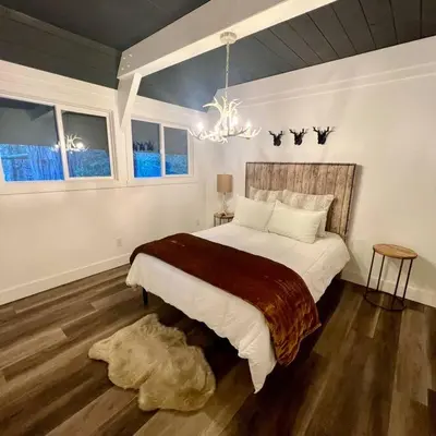 a bedroom with a large bed and a chandelier at Lake Arrowhead Lux Black Cabin in Lake Arrowhead
