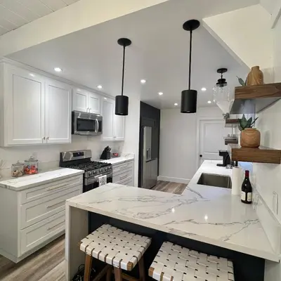 a kitchen with white cabinets and a large island with stools at Lake Arrowhead Lux Black Cabin in Lake Arrowhead