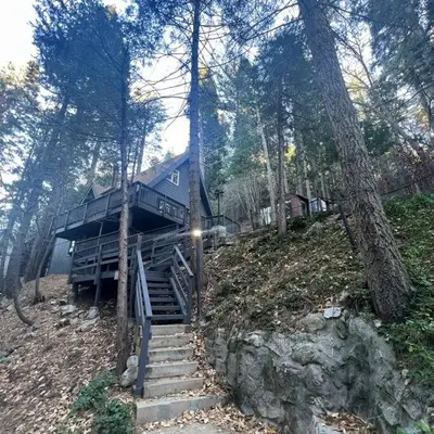 a house sitting on top of a hill with stairs at Lake Arrowhead Lux Black Cabin in Lake Arrowhead